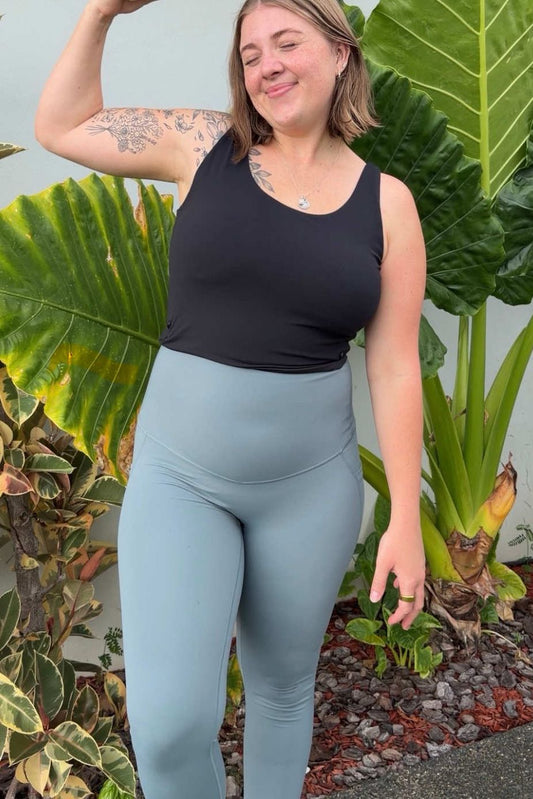 Woman flexing her arm outdoors with green plants in the background